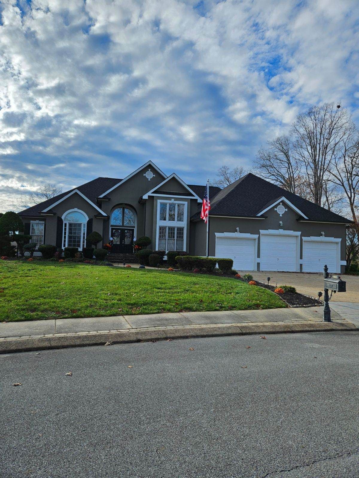 A large house with three garages and a large lawn in front of it.