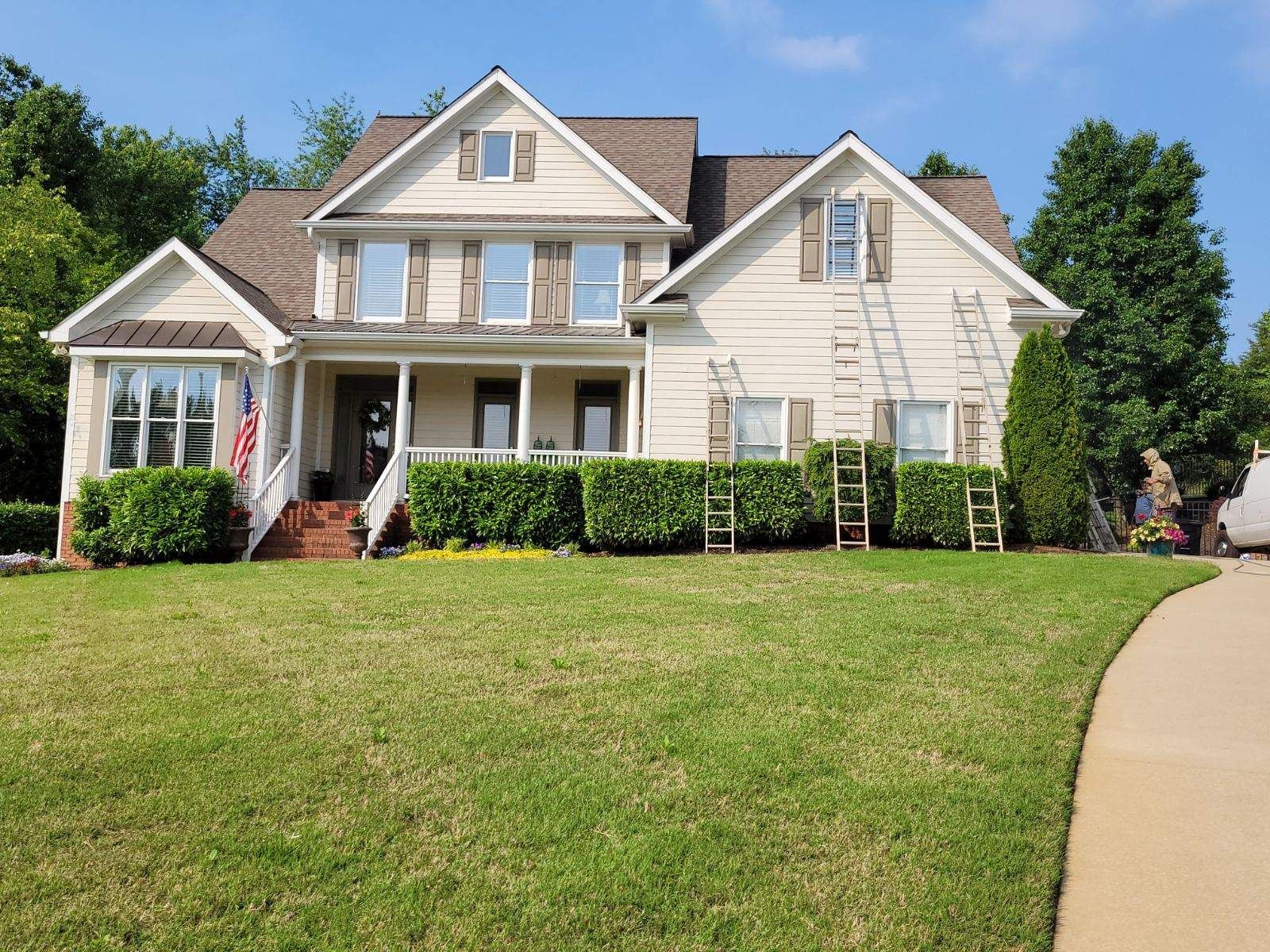 A large white house with a large lawn in front of it is being painted.