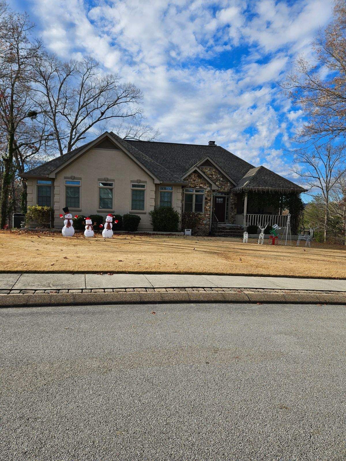A house with snowmen in front of it on a sunny day.