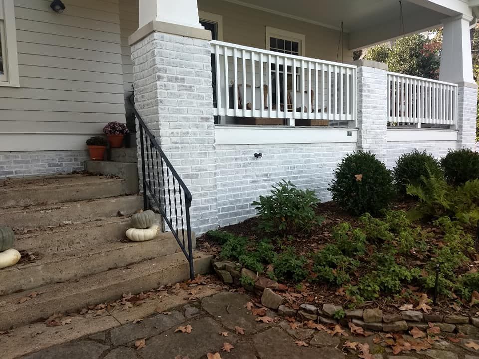 A white brick house with a porch and stairs