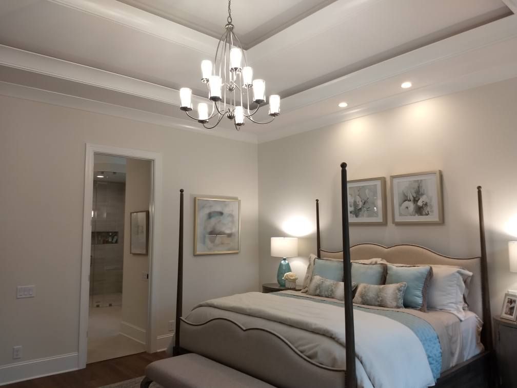 A bedroom with a four poster bed and a chandelier hanging from the ceiling.