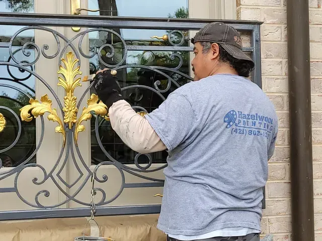 A man in a gray shirt is working on a wrought iron railing.