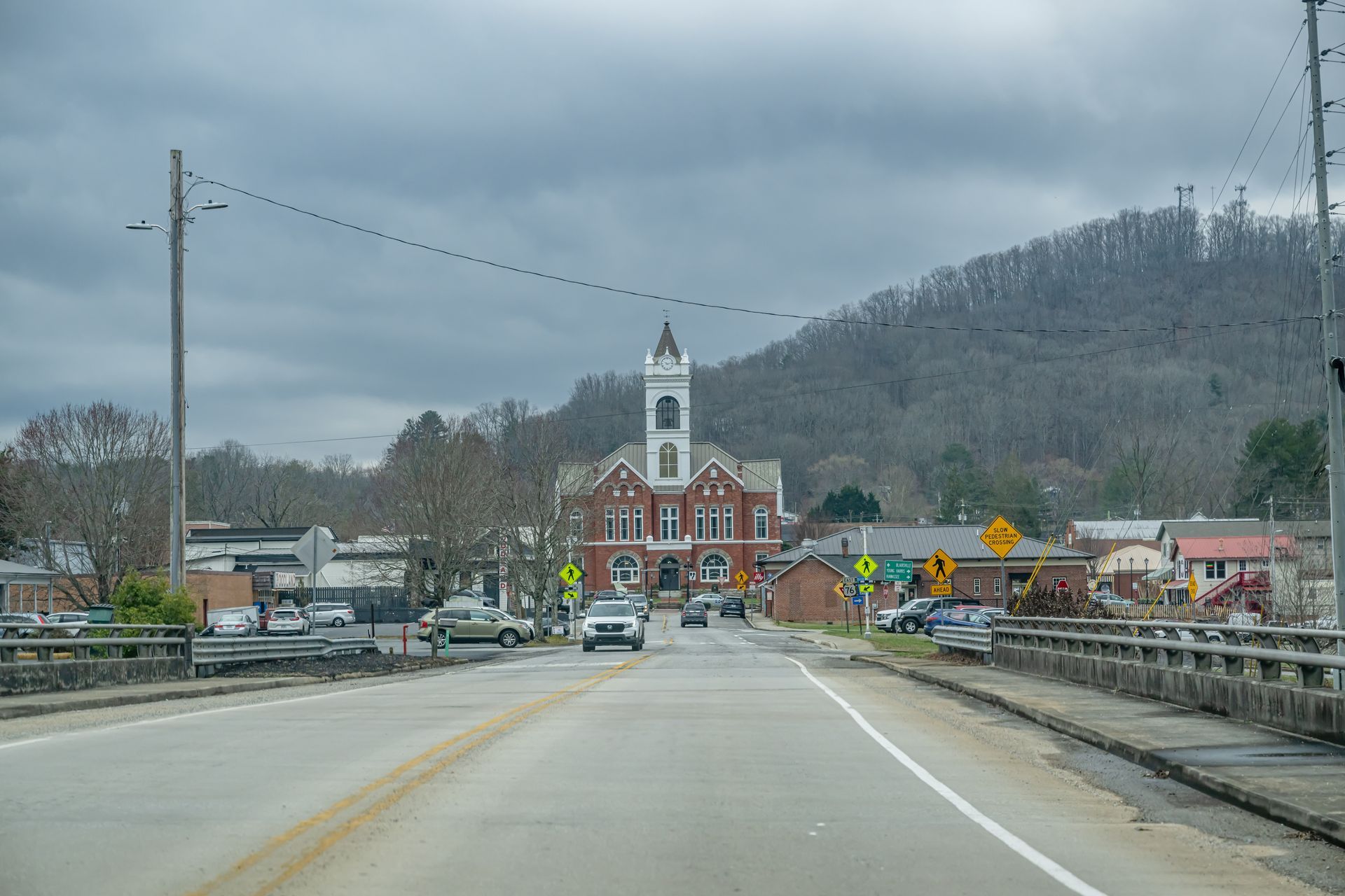 A car is driving down a road in front of a small town.
