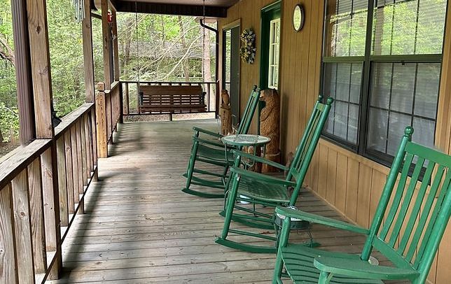 A porch with green rocking chairs and a table.