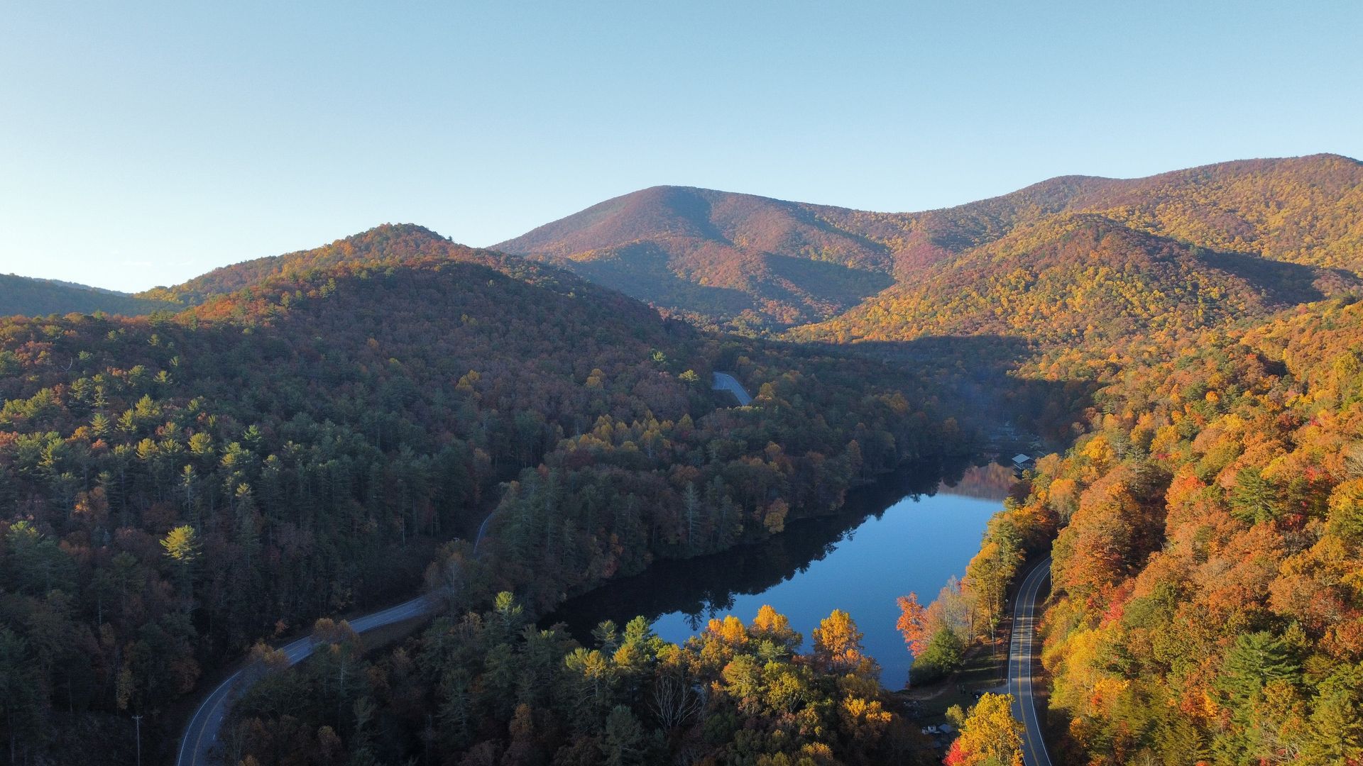 An aerial view of a lake surrounded by mountains and trees.