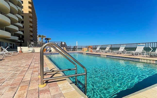 A large swimming pool with stairs leading to it in front of a building.