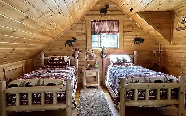 There are two beds in the attic of a log cabin.