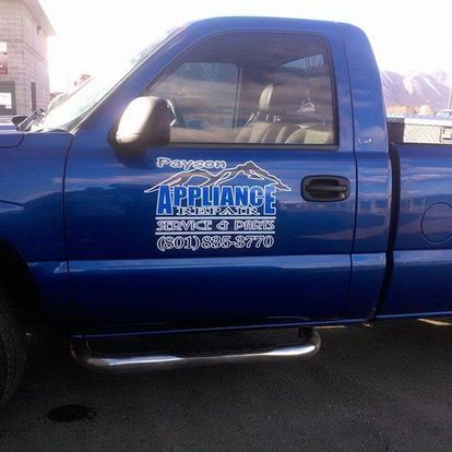 A blue appliance truck is parked in a parking lot