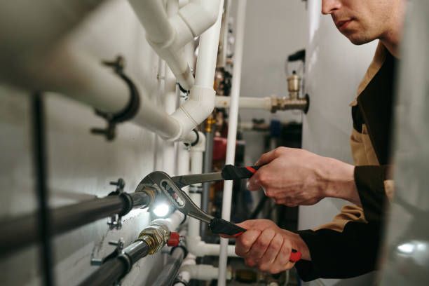 A man is working on a pipe with a wrench.