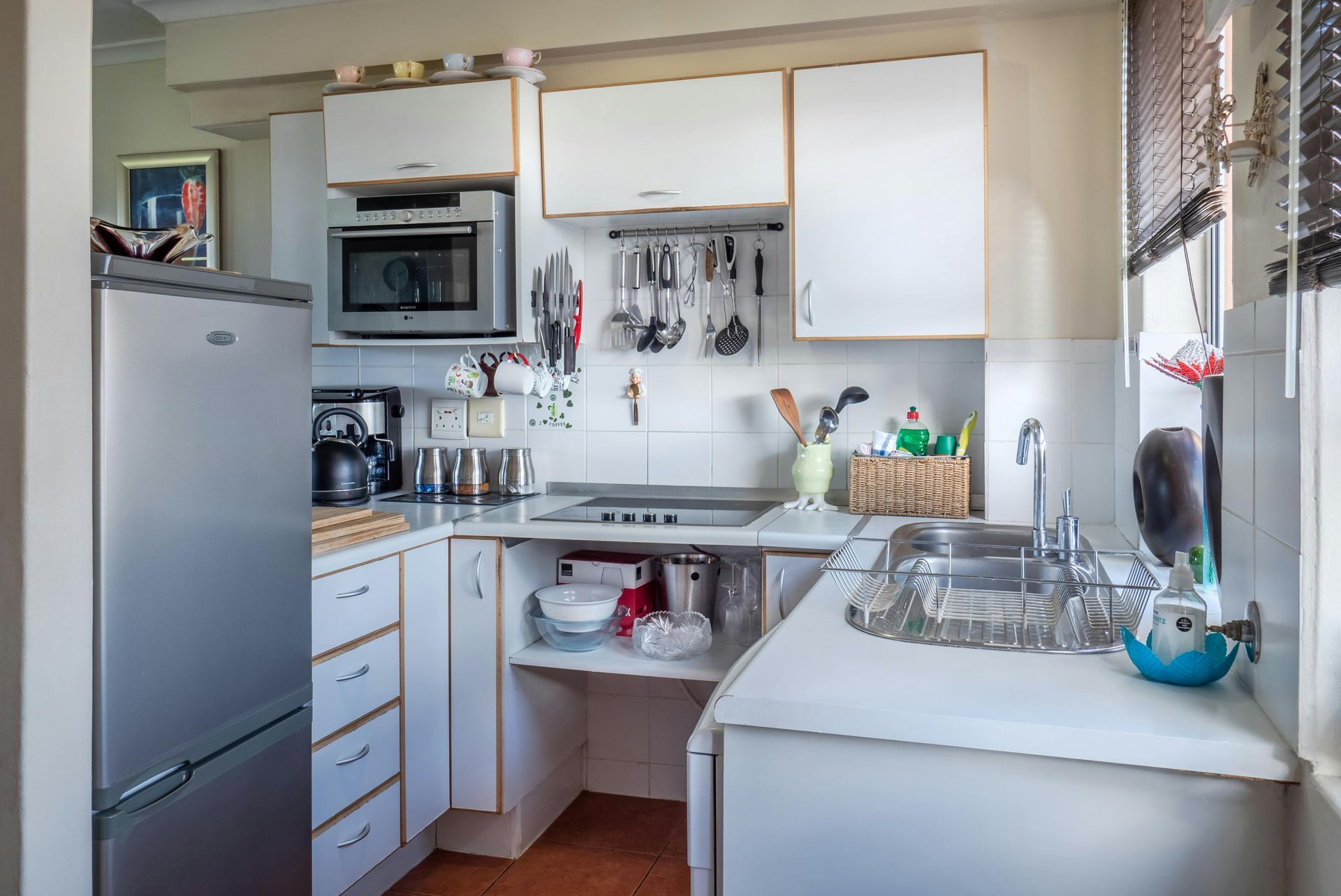 A kitchen with white cabinets , a stainless steel refrigerator , a sink , and a microwave.