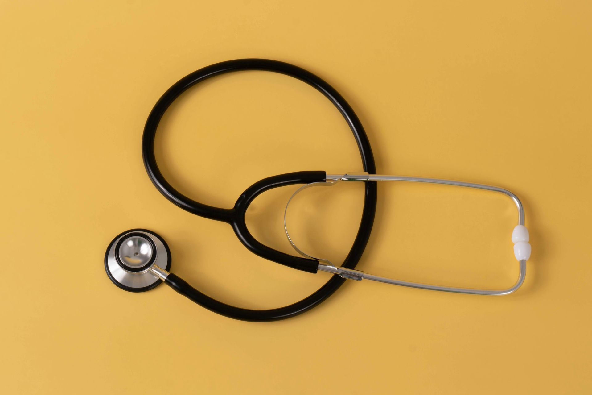 Black stethoscope on a yellow background