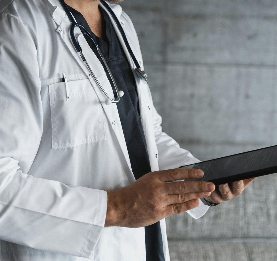 Doctor in white coat using a tablet with a stethoscope around the neck
