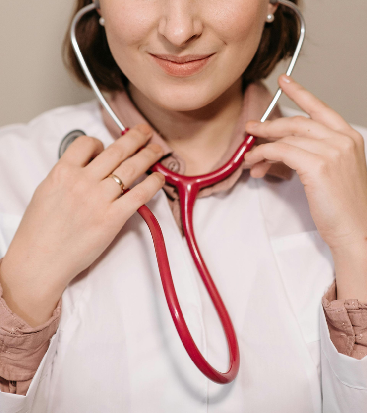 Person adjusting a red stethoscope over a white coat