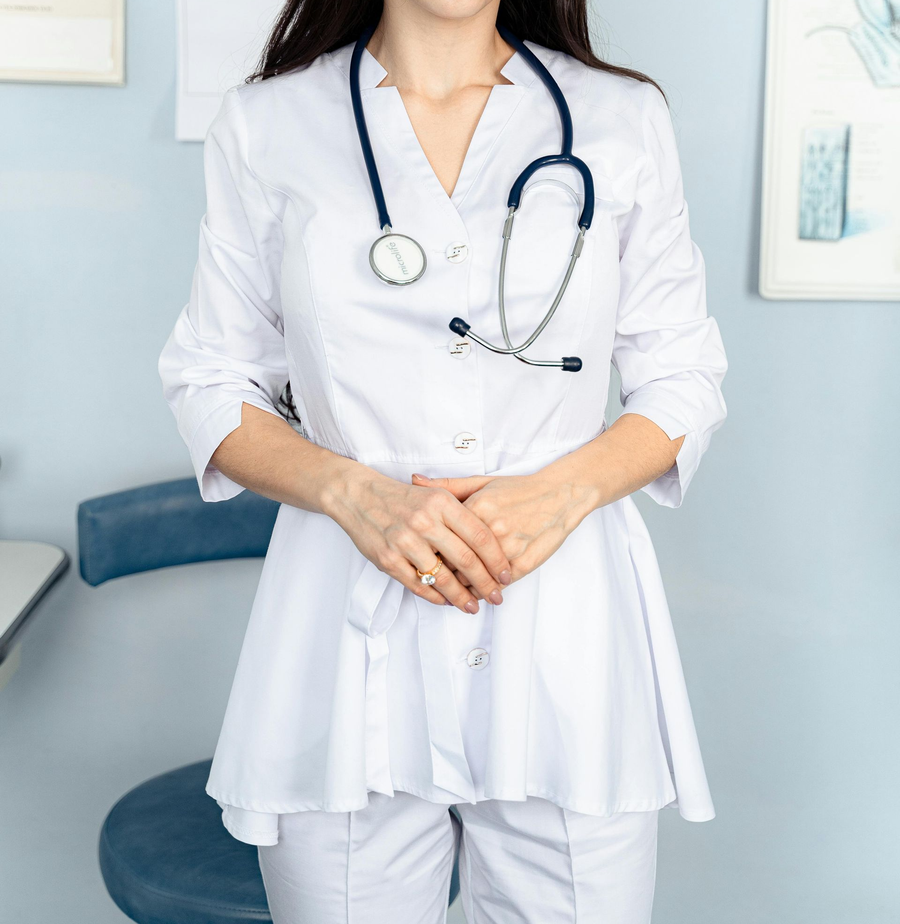 Medical professional in a white coat with stethoscope standing in a clinic office