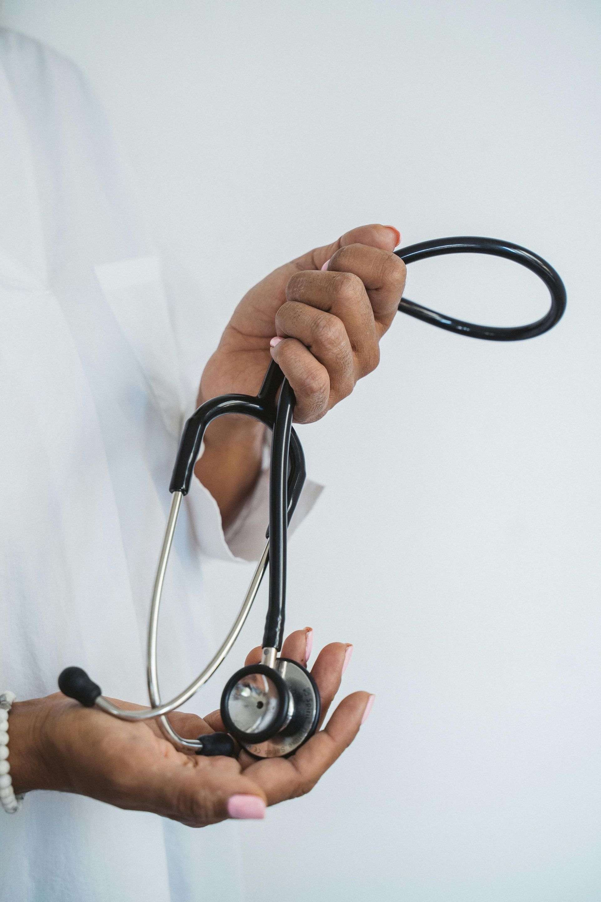 Person holding a black stethoscope against a white background