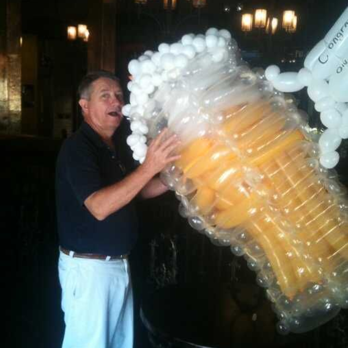 Magician in purple vest performing on stage with raised hands, audience in foreground.