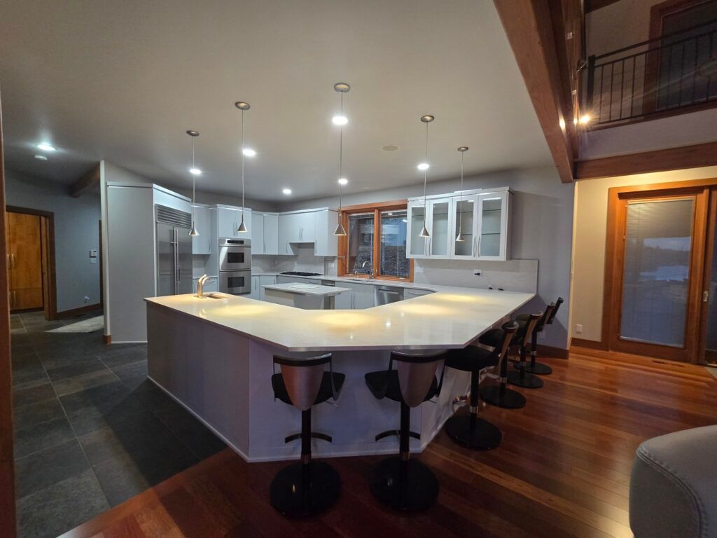 Modern kitchen with a large island, bar stools, and overhead lights.