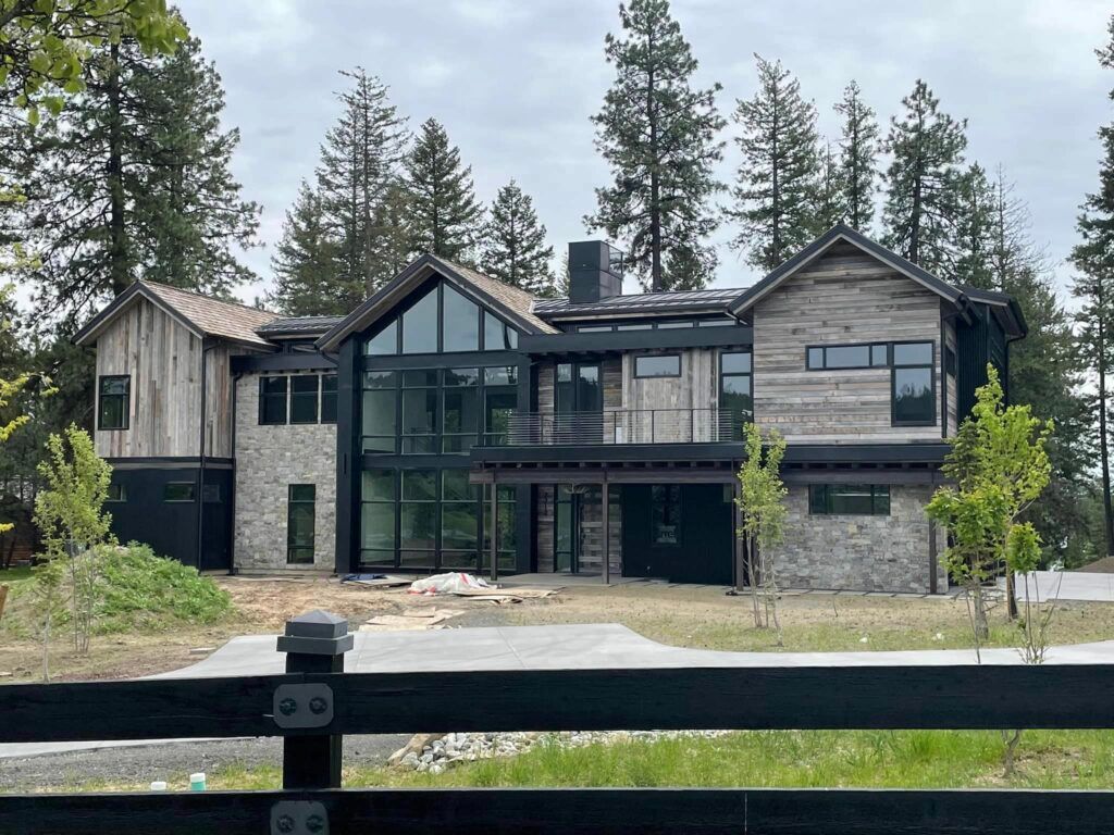 Modern rustic house with stone, wood siding, and large glass windows.
