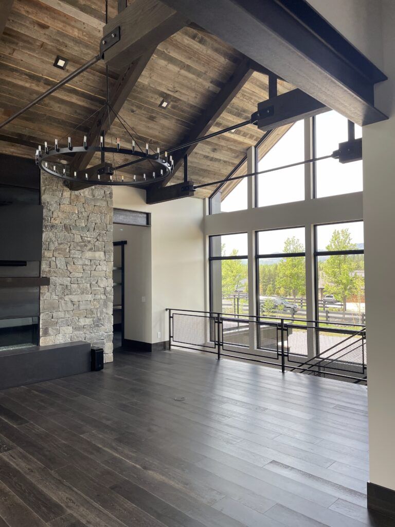 Interior of a room with dark wood floors, high ceiling, large windows, and stone accent wall.