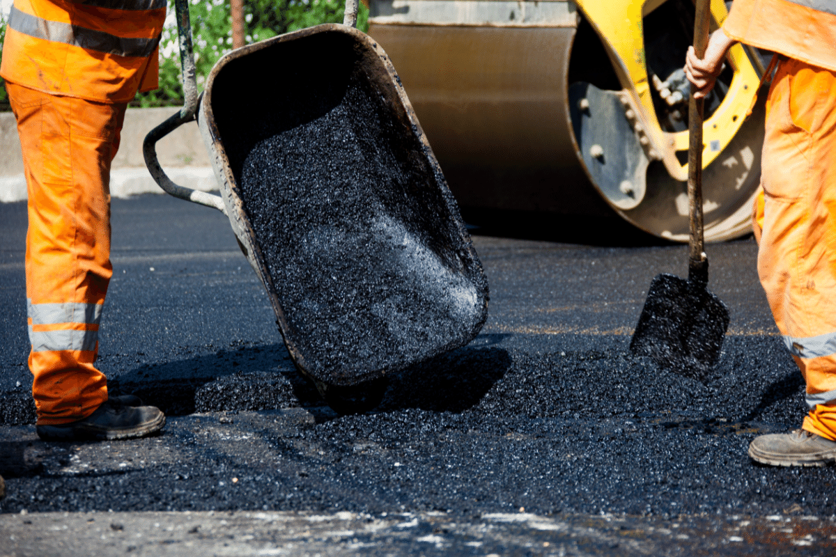 worker leveling fresh asphalt on a road construction