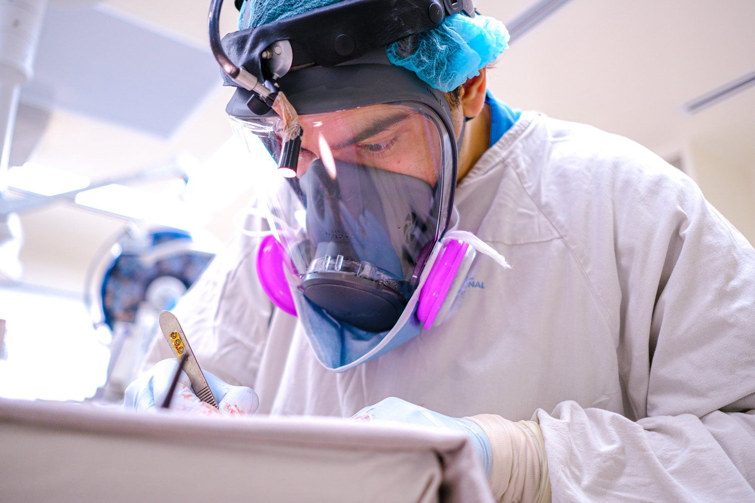 Cirujano usando equipo de protección en un quirófano, concentrado en el procedimiento.