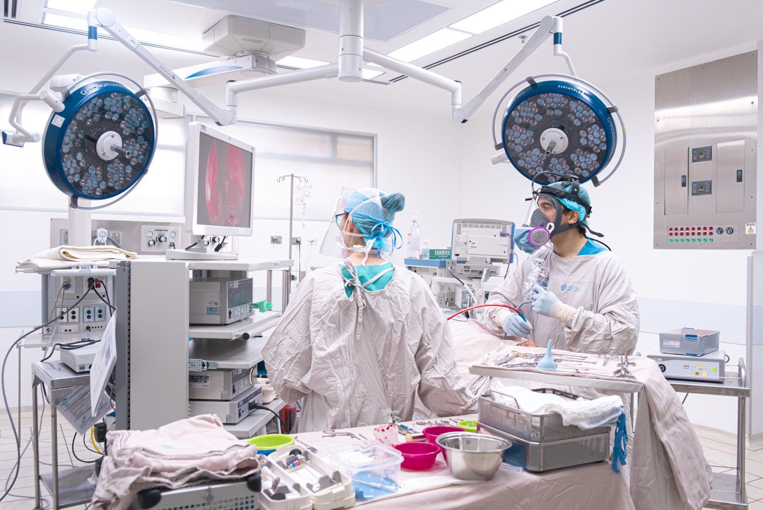Cirujanos con equipo de protección operando en un quirófano muy iluminado.