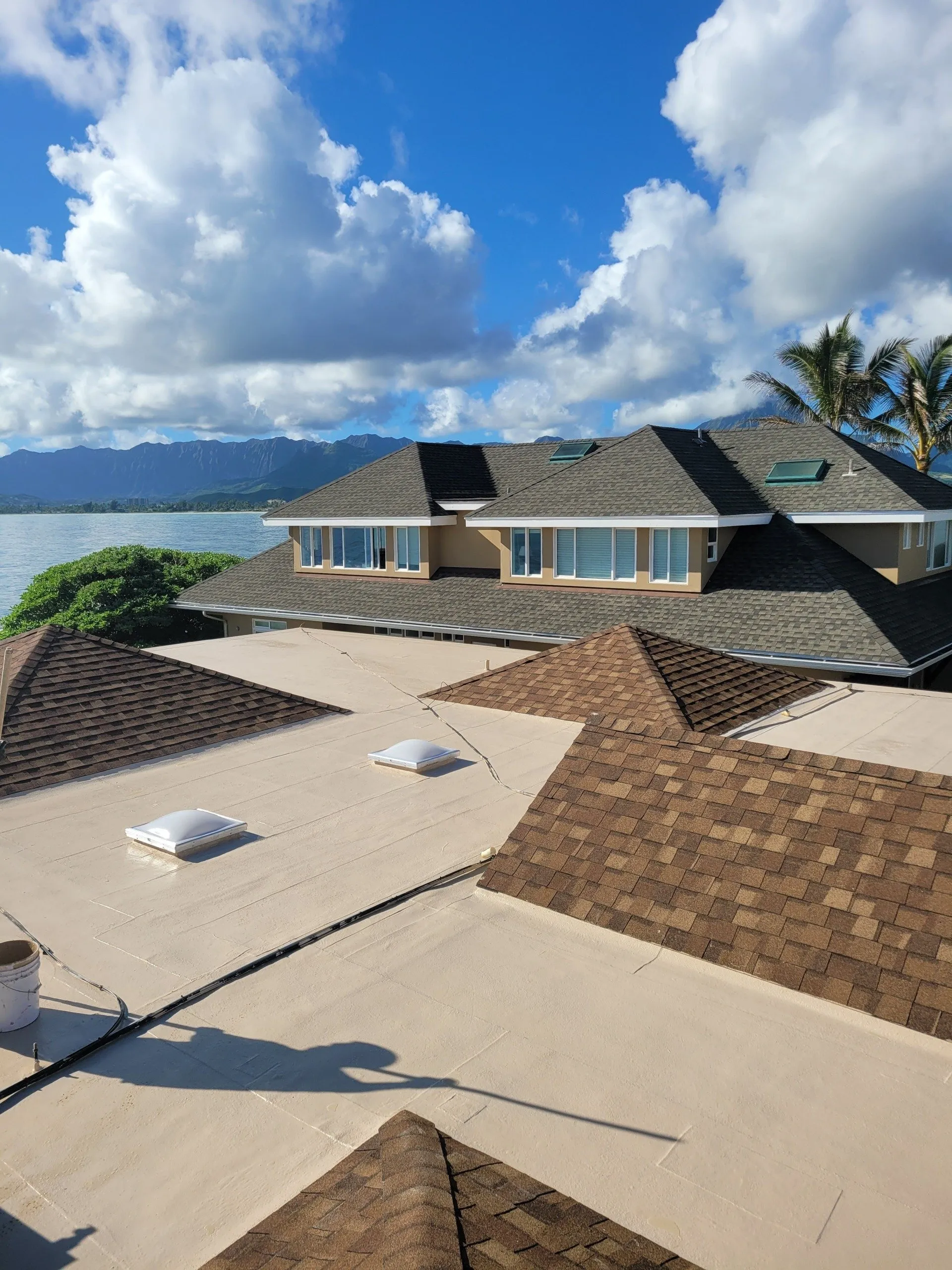 A large house with a lot of roofs and a view of the ocean.