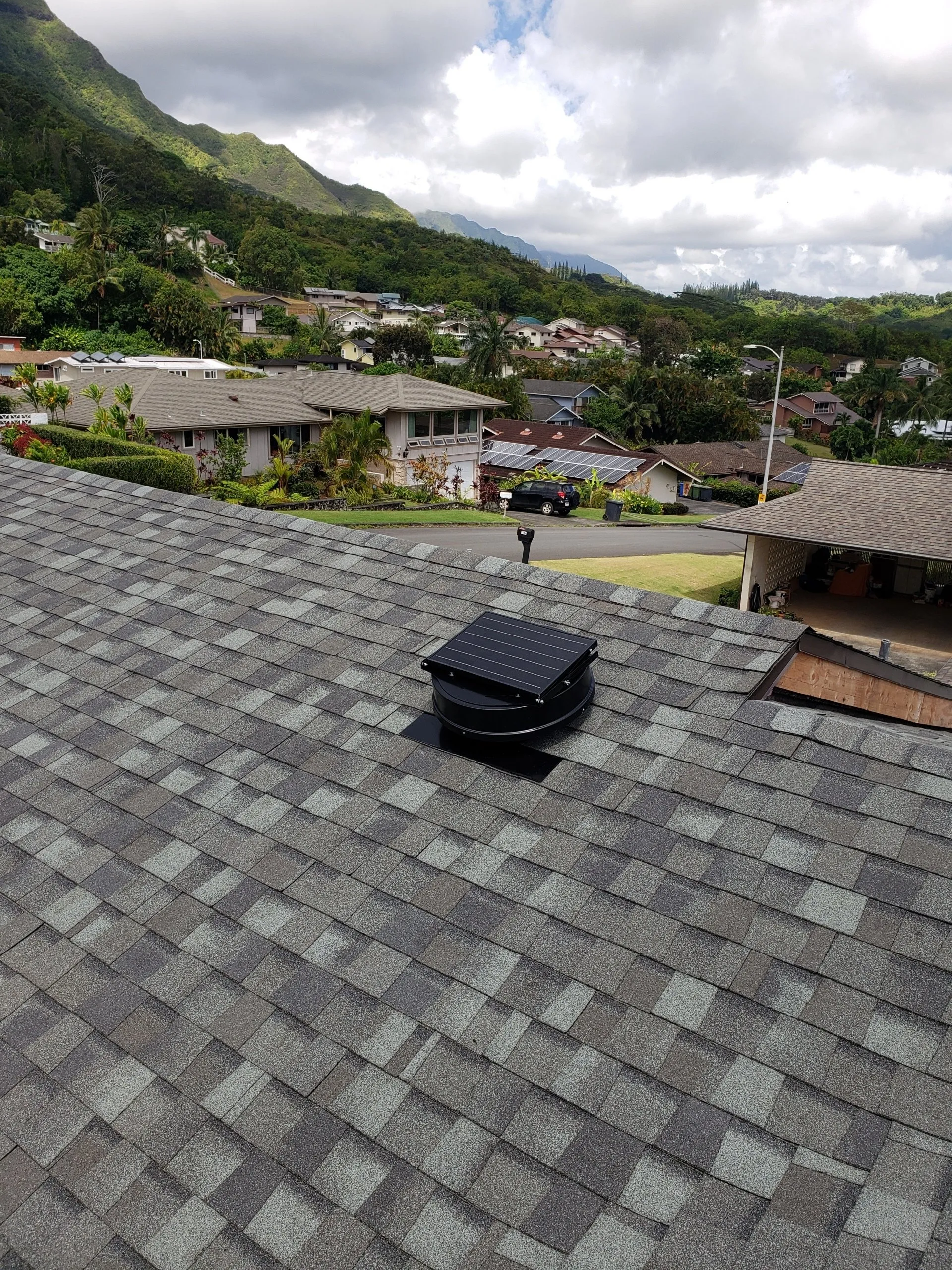 A roof with a solar panel on it and mountains in the background.
