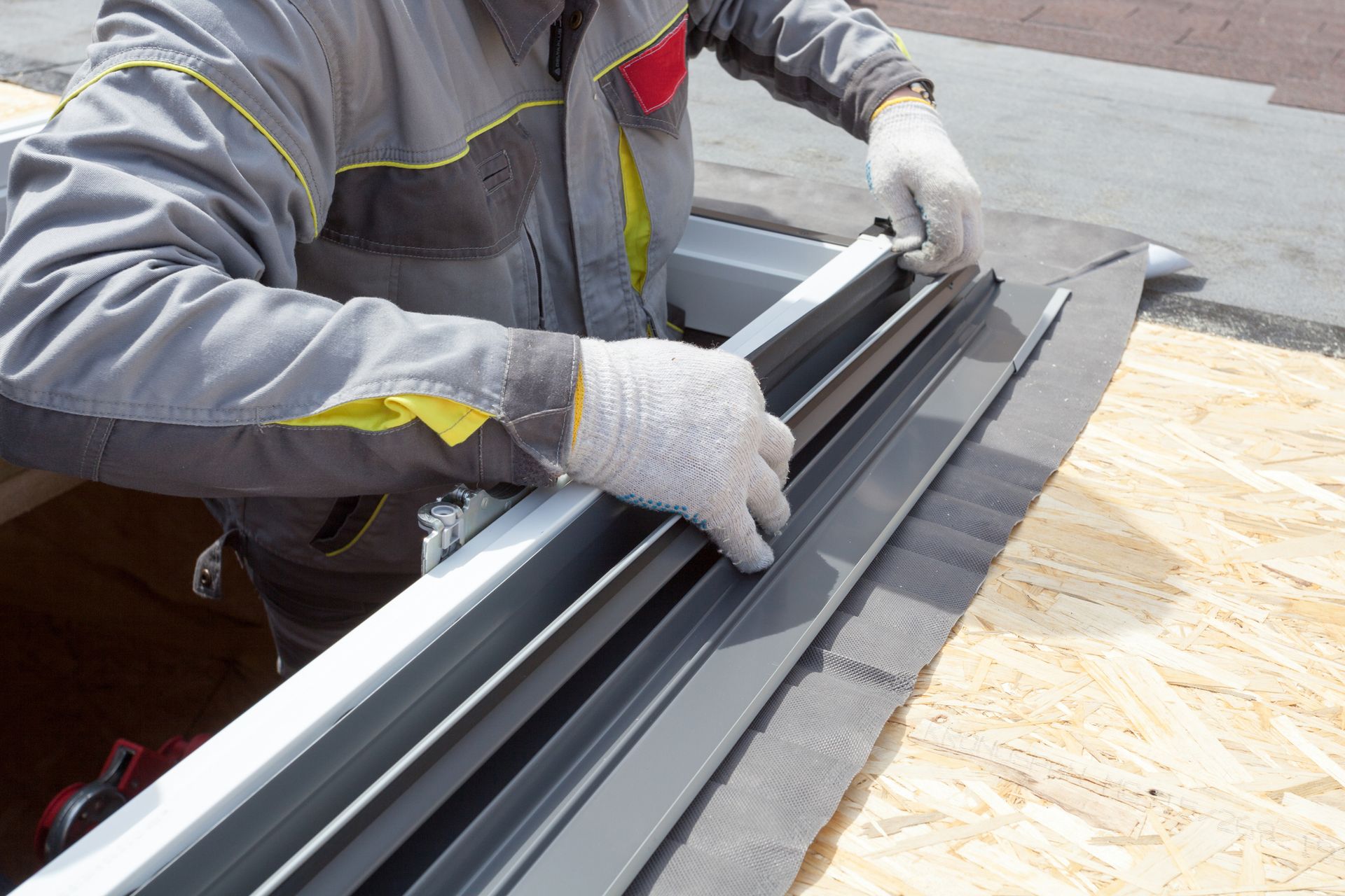A man is working on a window on a roof.
