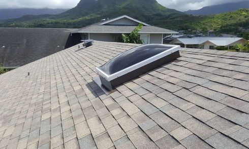 A roof with a skylight and mountains in the background.