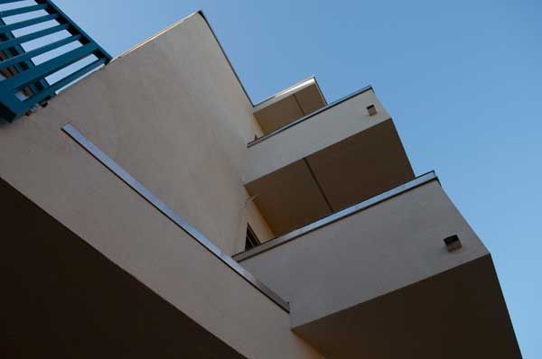 View of beige building with boxy balconies, blue sky.