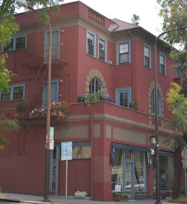 Red building with blue trim, featuring arched windows and a storefront.