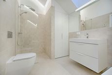 Modern bathroom with white fixtures, beige tile walls, and a large mirror.