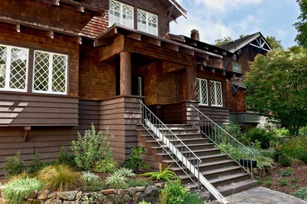 Brown wooden Craftsman house with stone steps, a covered porch, and leaded glass windows.