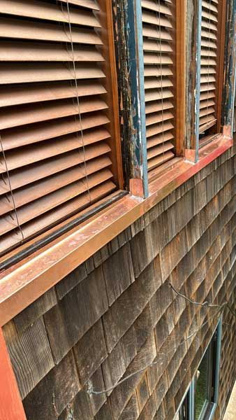 Wooden shingles, copper flashing, and shuttered windows.