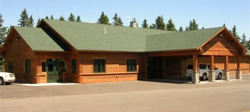 The front door of a house with a porch and plants in front of it.