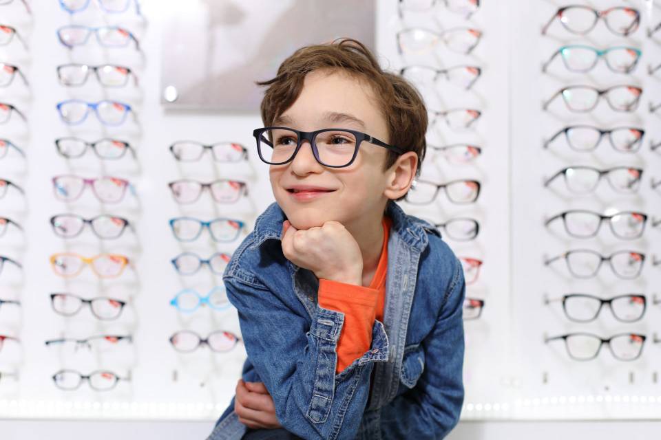 bambino con occhiali da vista in negozio di ottica