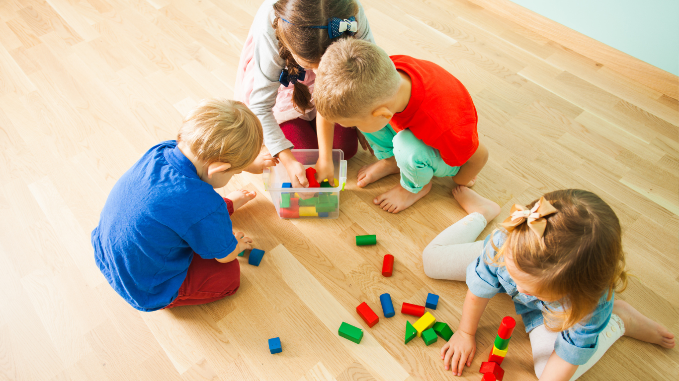 A group of children are sitting on the floor playing with lego blocks.