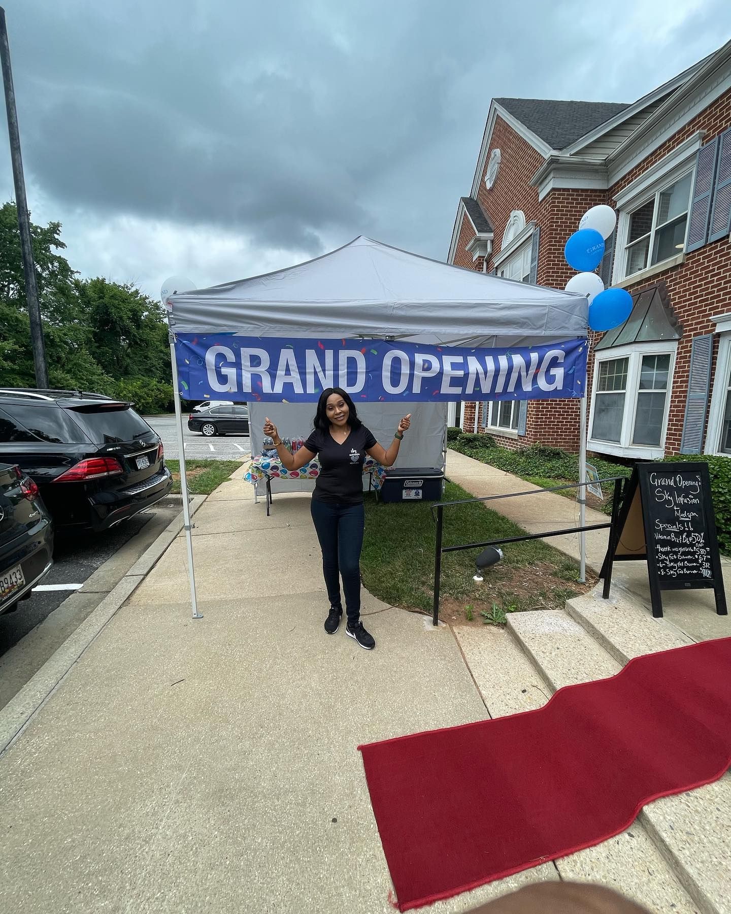 A woman is standing in front of a canopy that says `` grand opening ''.