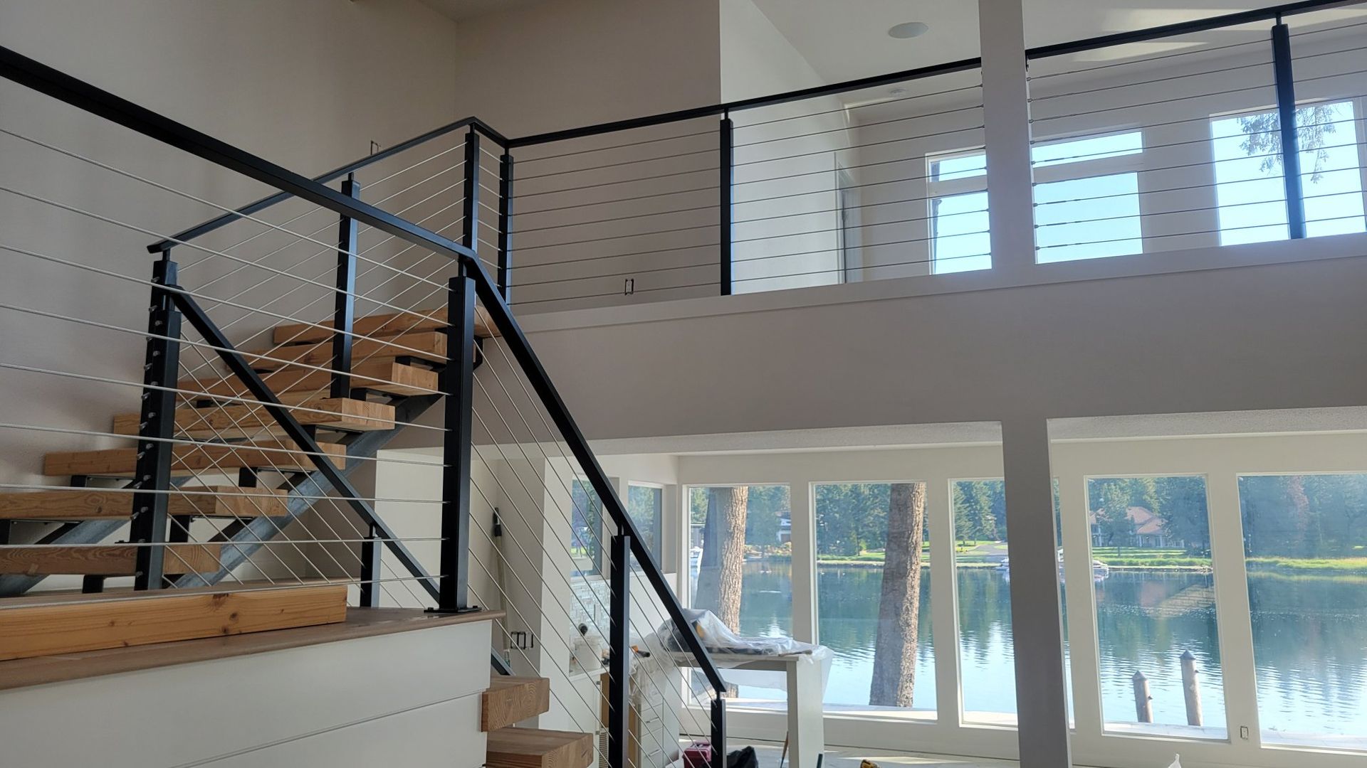 Interior view of a modern home with a staircase featuring black metal railings and cable infills.