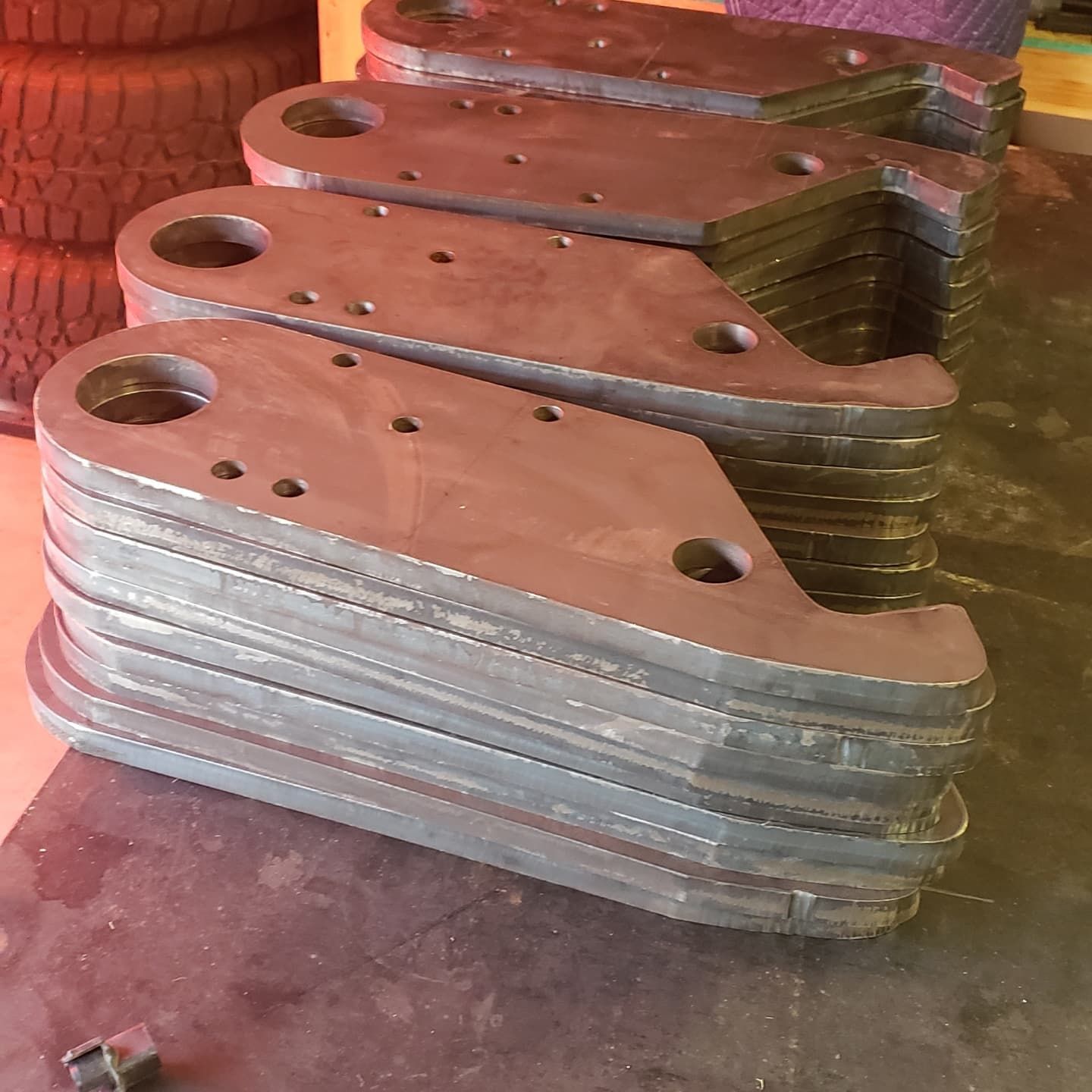 Stacks of metal plates with various holes and angled edges, possibly for manufacturing.