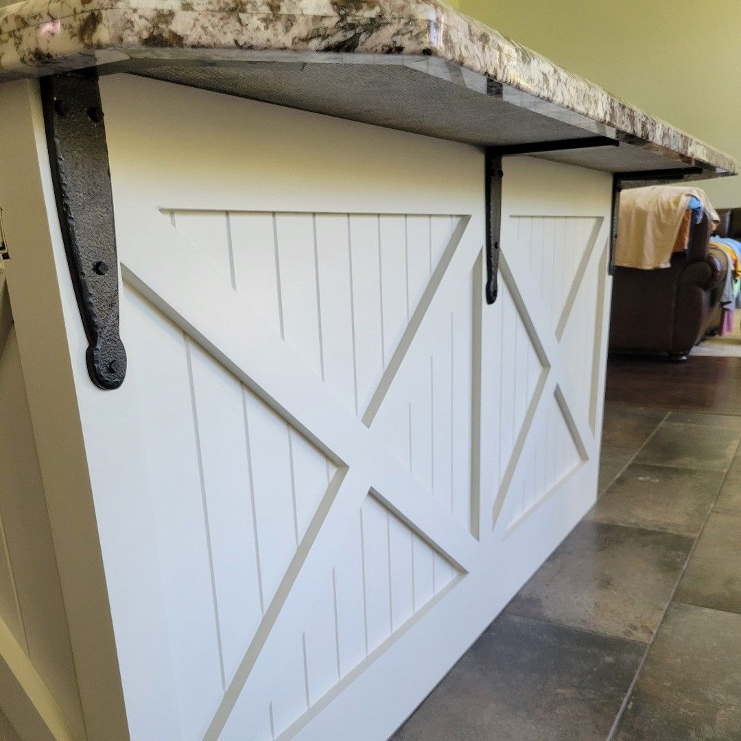 White kitchen island with a farmhouse design, granite countertop, and black metal supports.