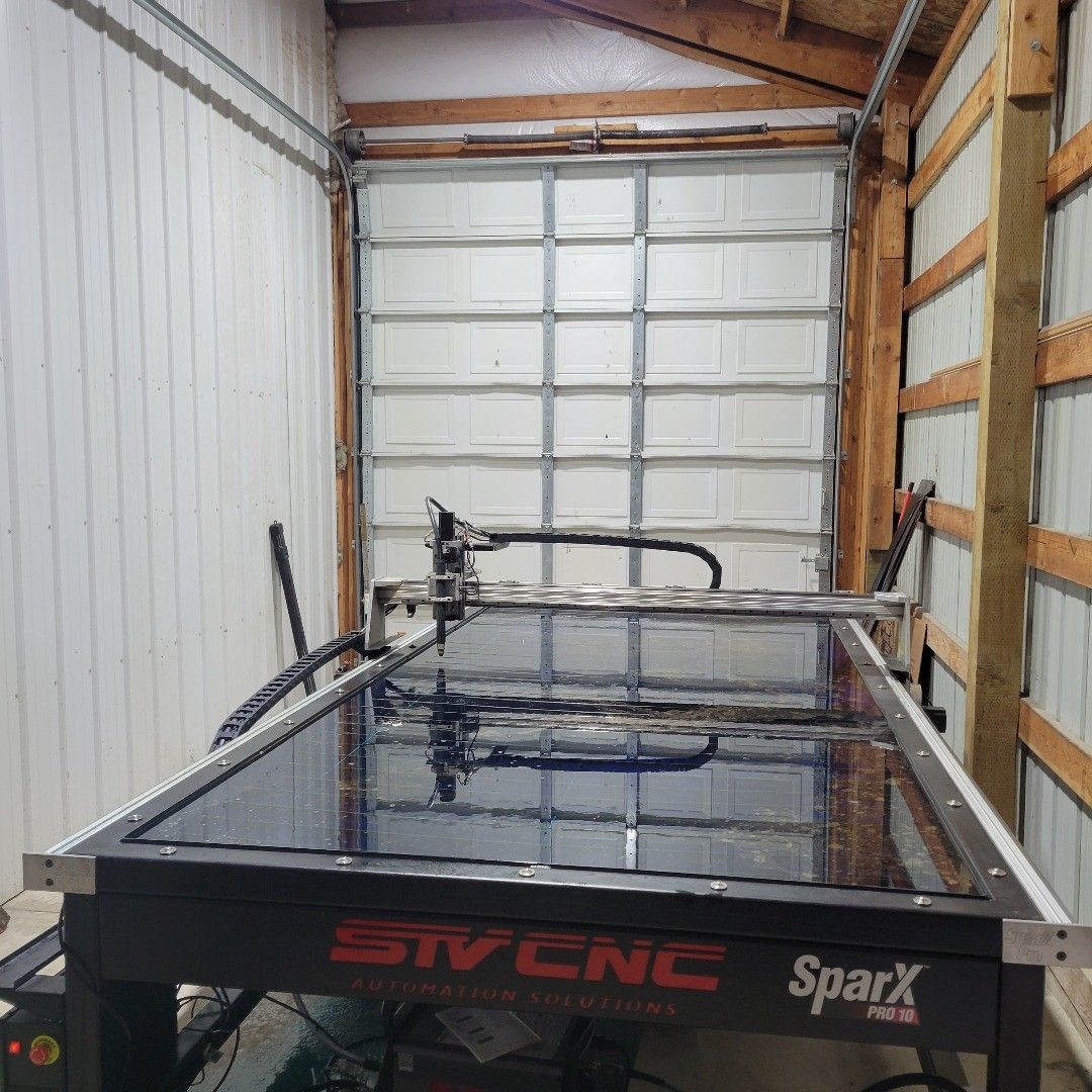 A large STV CNC SparX Pro machine sits in front of a closed garage door.