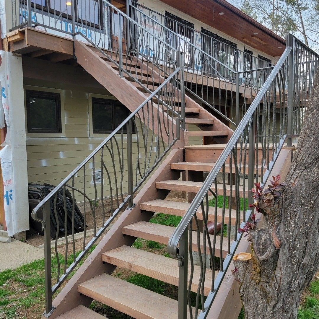 Outdoor wooden staircase with metal railings leading to a deck.