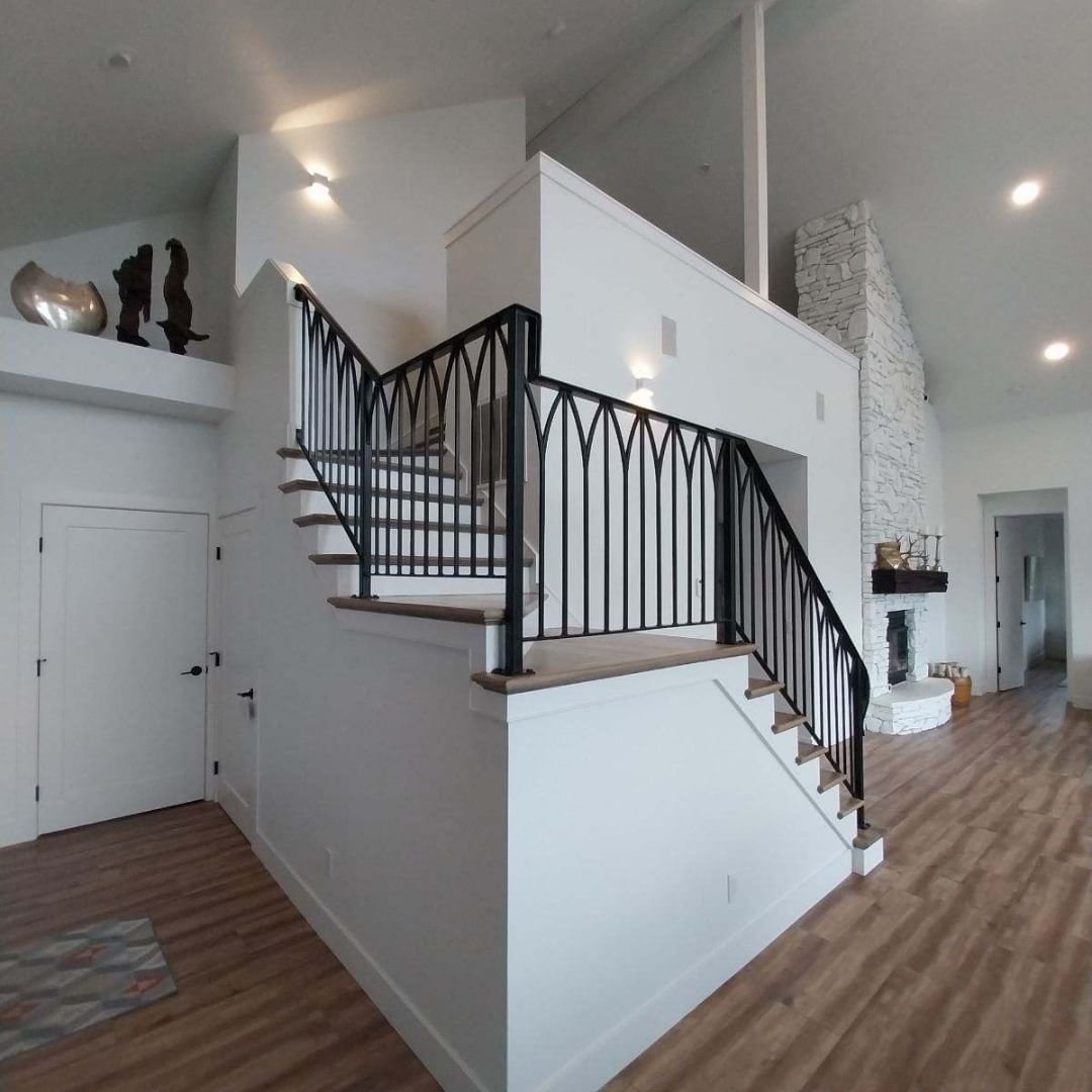 Interior view of a modern home with a staircase, black railing, and white walls.