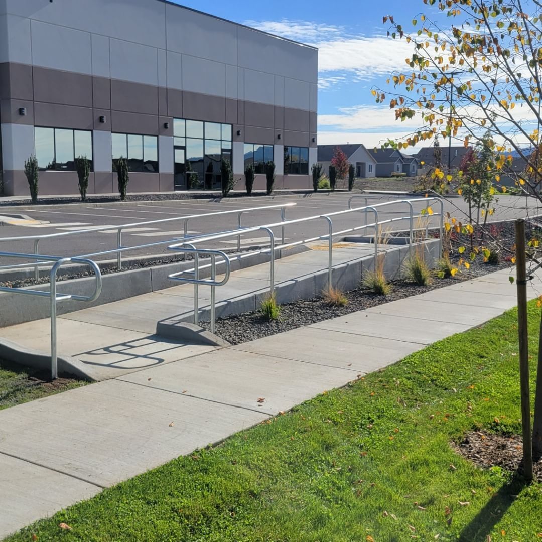 Exterior of a building with a wheelchair ramp, sidewalk, and grassy area. The sky is blue.