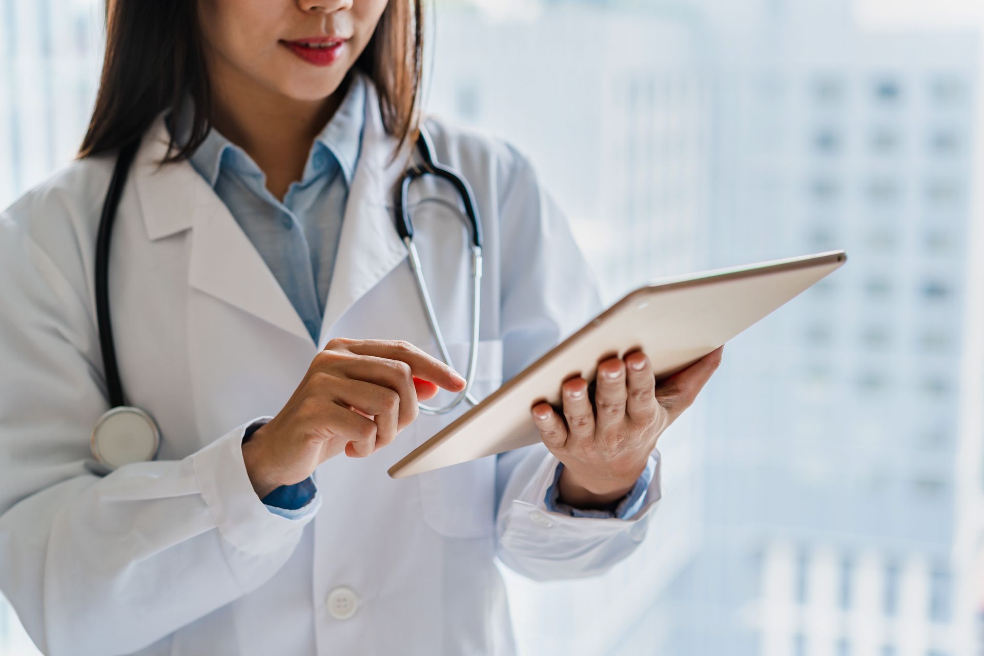 Female doctor working on smart device in the medical office at the hospital.