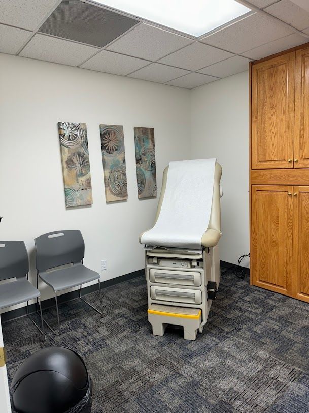 A doctor 's office with a examination table and chairs.