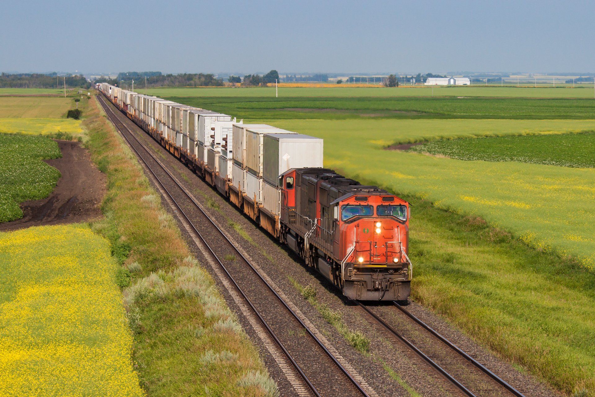 Container train on one of two tracks crossing colorful prairie