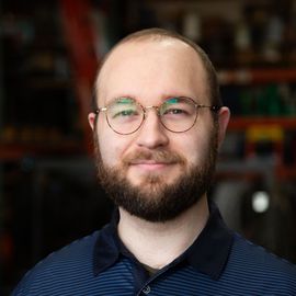 A man with a beard and glasses is smiling for the camera.